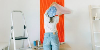 Back View of a Woman Putting Up a Wallpaper on the Wall
